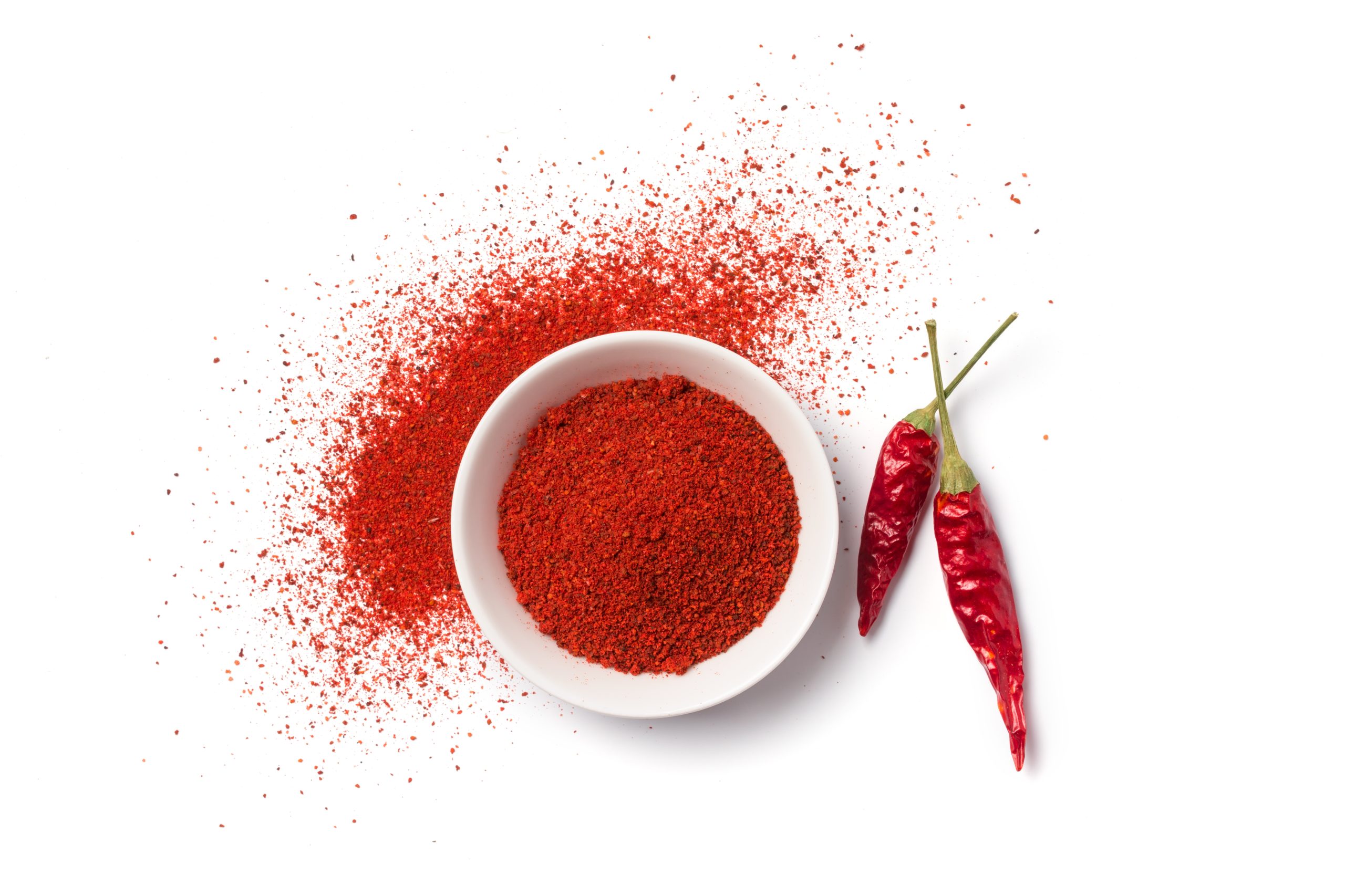 Top view of bright red pepper spice in bowl for aromatic food isolated on white background